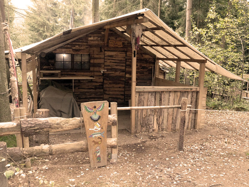 Hütte mit Zaun und Tafel mit indianischer Verzierung