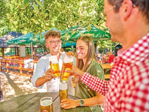 Freunde stoßen mit einem Bier von Hacklberg an