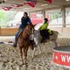 Mensch auf seinem Pferd in einer Reithalle