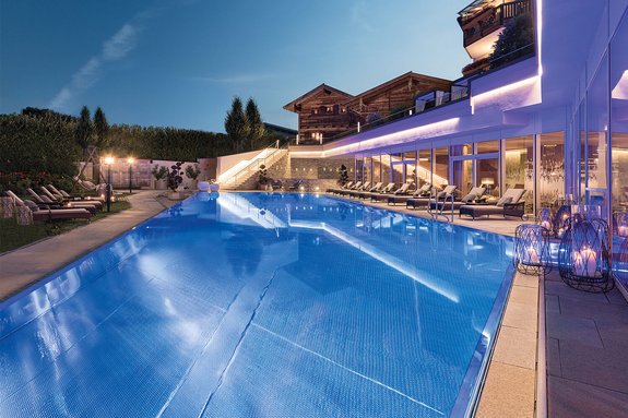 Das 5* Wellness- & Sporthotel Jagdhof Hotelanlage mit Blockhütten, Pool und Liegen
