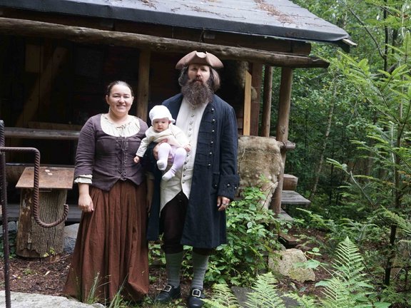 Mann mit Baby auf dem Arm und Frau stehen vor Haus 