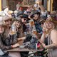 Menschen mit Cowboyhüten sitzen an einem Biertisch