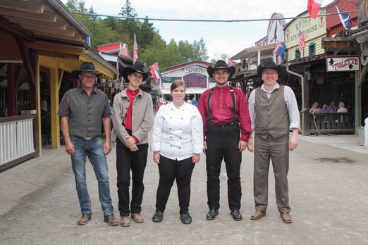 Auszubildende in Pullman City Vier Männer mit Cowboyhüten und eine Köchin
