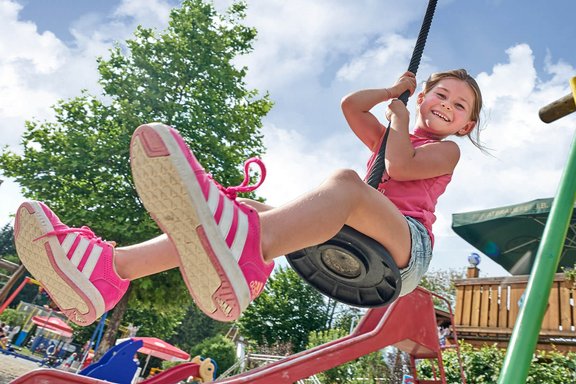 Mädchen schaukelt auf Spielplatz