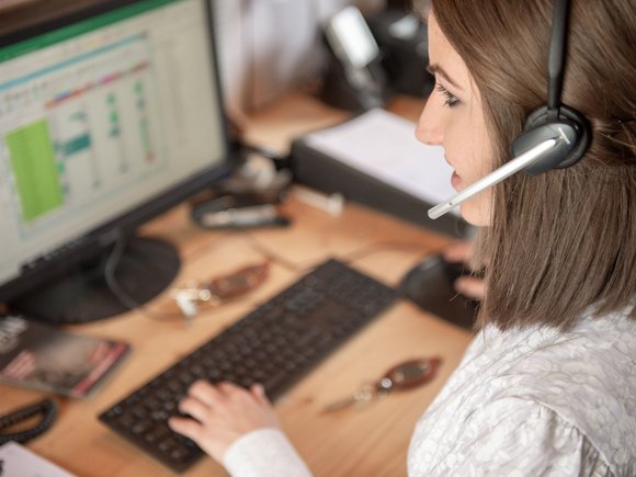 Frau arbeitet mit Headset am PC