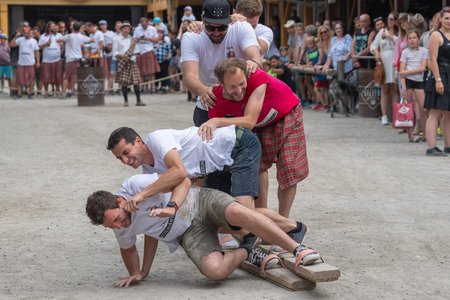 Männer stehen auf langen Balken und fallen um.
