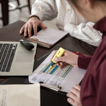Veranstaltungskauffrau/-mann Zwei Personen an einem Tisch mit Laptop und Notizzettel