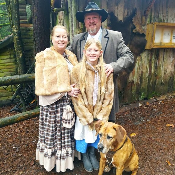 Familie Schulz und ihr Hund posieren für die Kamera und lächeln.