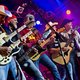 Personen mit Gitarren und Bass spielen auf einer Bühne