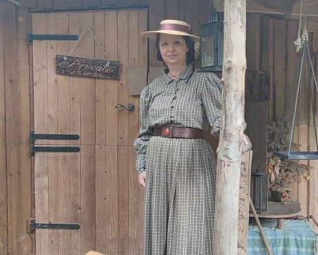 Alison Lawson steht vor einem Holzhaus auf Veranda in einem Wald