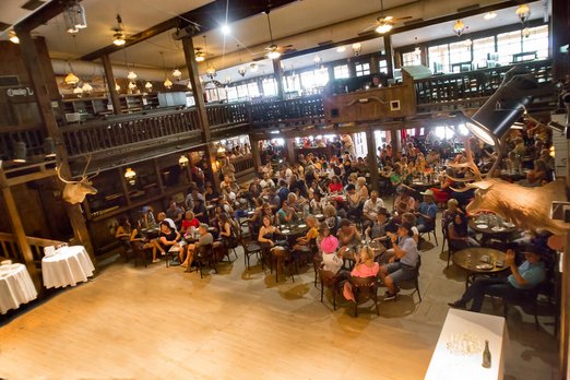 Menschen sitzen um Tische in der Music and Dance Hall in Pullman City