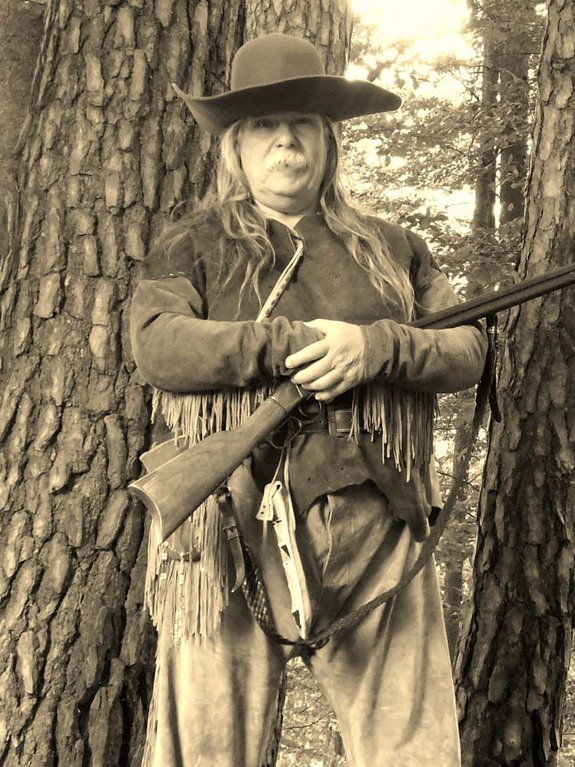 alter Mann mit Hut in indianischer Kleidung und Gewehr