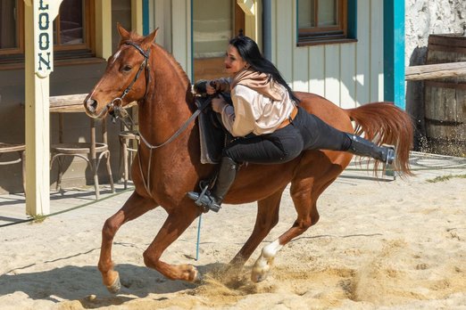 Frau steigt auf ein galoppierendes Pferd