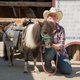 Frau kniet neben gesatteltem Pony