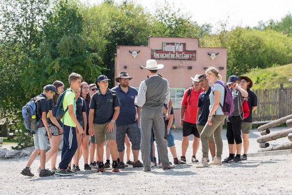 Menschen stehen um Mann in Cowboykleidung