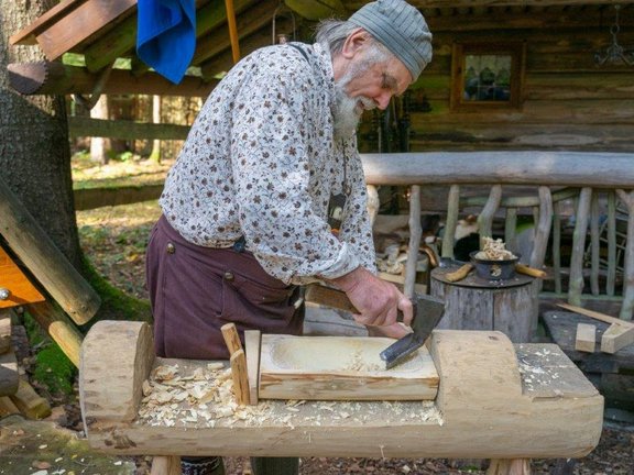Mann schnitzt eine Schale aus einem Holzblock