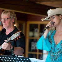 Jill & Joe Frau singt in ein Mikrofon, Mann spielt Gitarre