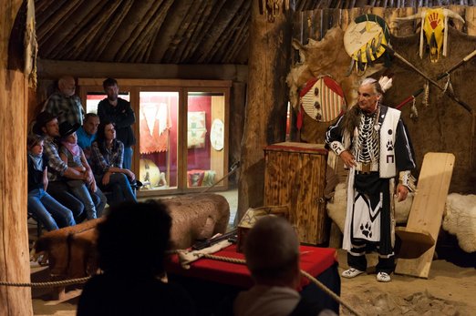 Indianer vor Wand mit traditionellen Schilden und Speren