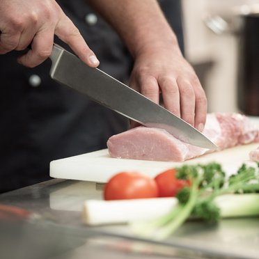 Fachkraft Küche Mann schneidet Fleisch