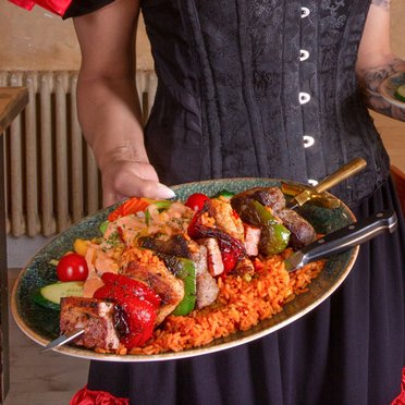 Tellerträger/in Frau trägt 3 Teller mit Essen